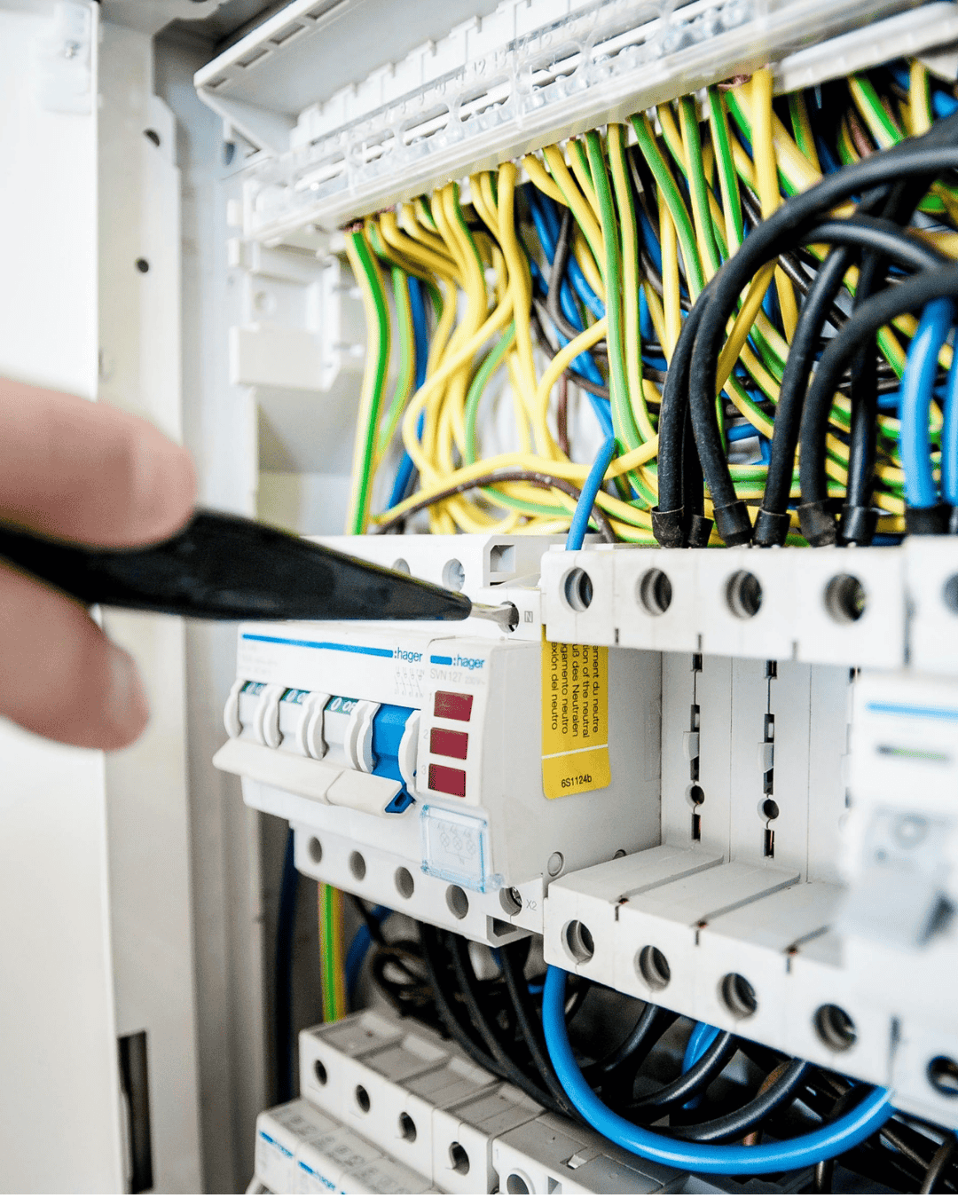 Una mano di un elettricsta all'opera sui cavi elettrici di un quadro elettrico a Roma